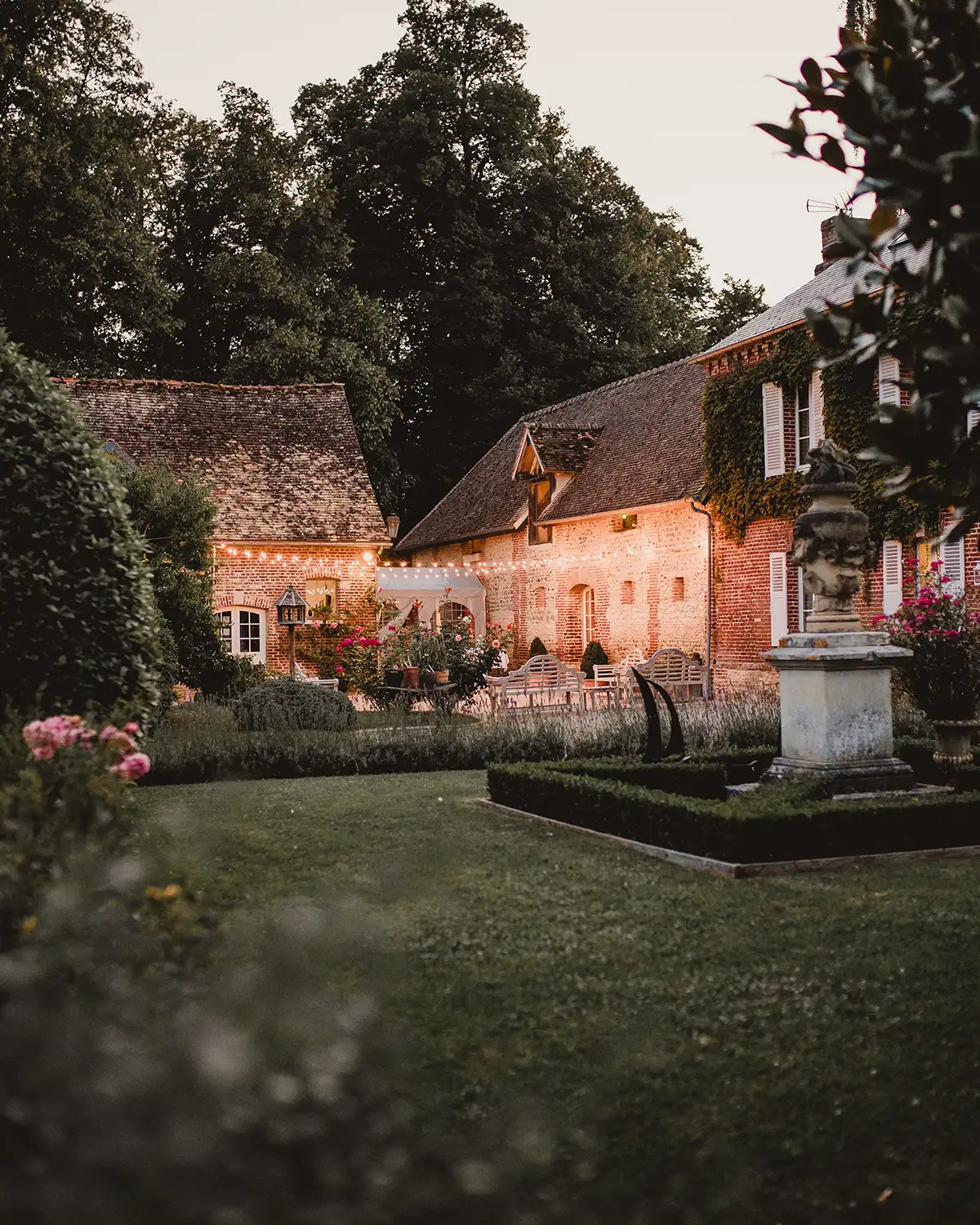 Le domaine de L'Orangerie de Vatimesnil au crépuscule : jardin à la française et bâtisses en brique — salle de réception mariage à Vatimesnil, Eure
